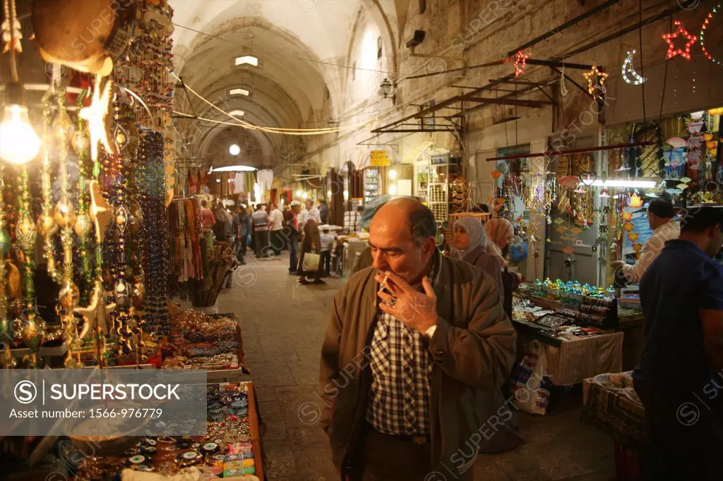 A man examines goods while smoking at a market in the old city section of Jerusalem