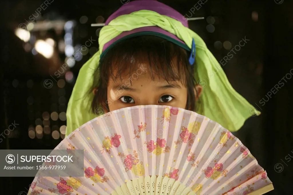 A young Longneck girl hides behind her fan Approximately 300 Burmese refugees in Thailand are members of the indigenous group known as the Longnecks T...