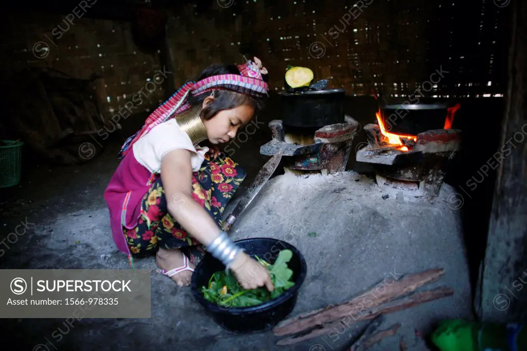 A young Longneck girl prepares a meal with greens in her home Approximately 300 Burmese refugees in Thailand are members of the indigenous group known...