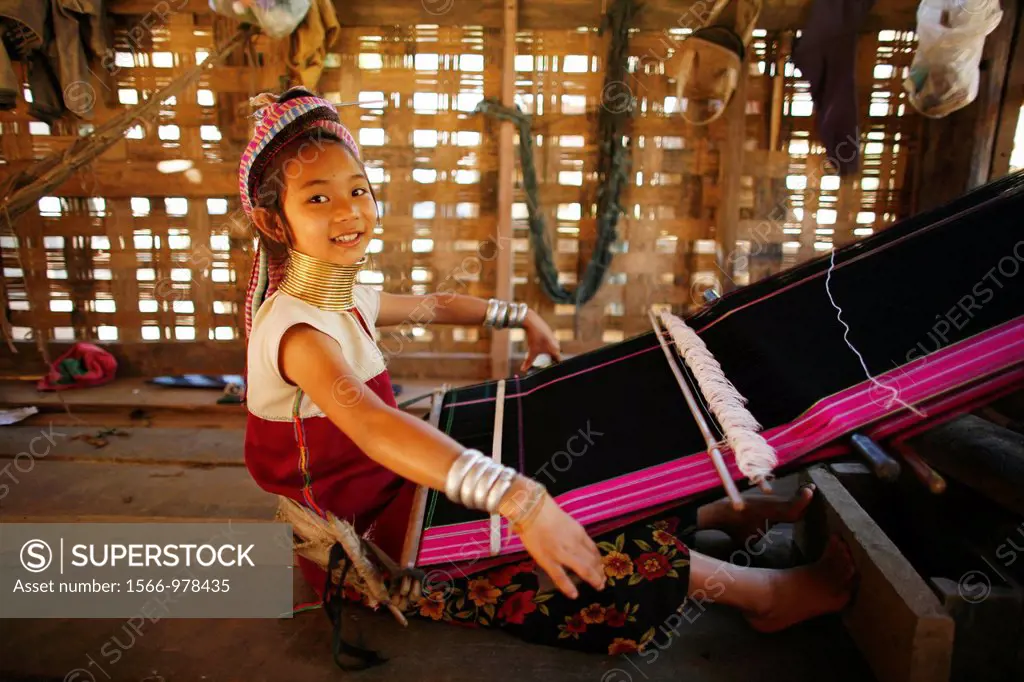 A young Longneck girl smiles as she weaves cloth on a loom Approximately 300 Burmese refugees in Thailand are members of the indigenous group known as...