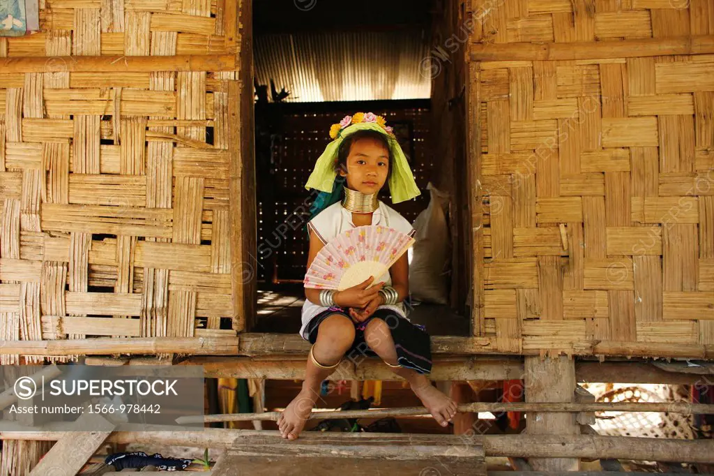 A young Longneck girl holding a fan sits outside a house in the village Approximately 300 Burmese refugees in Thailand are members of the indigenous g...