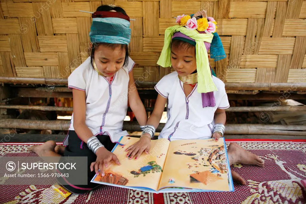 Two young Longneck girls look at a book together Approximately 300 Burmese refugees in Thailand are members of the indigenous group known as the Longn...