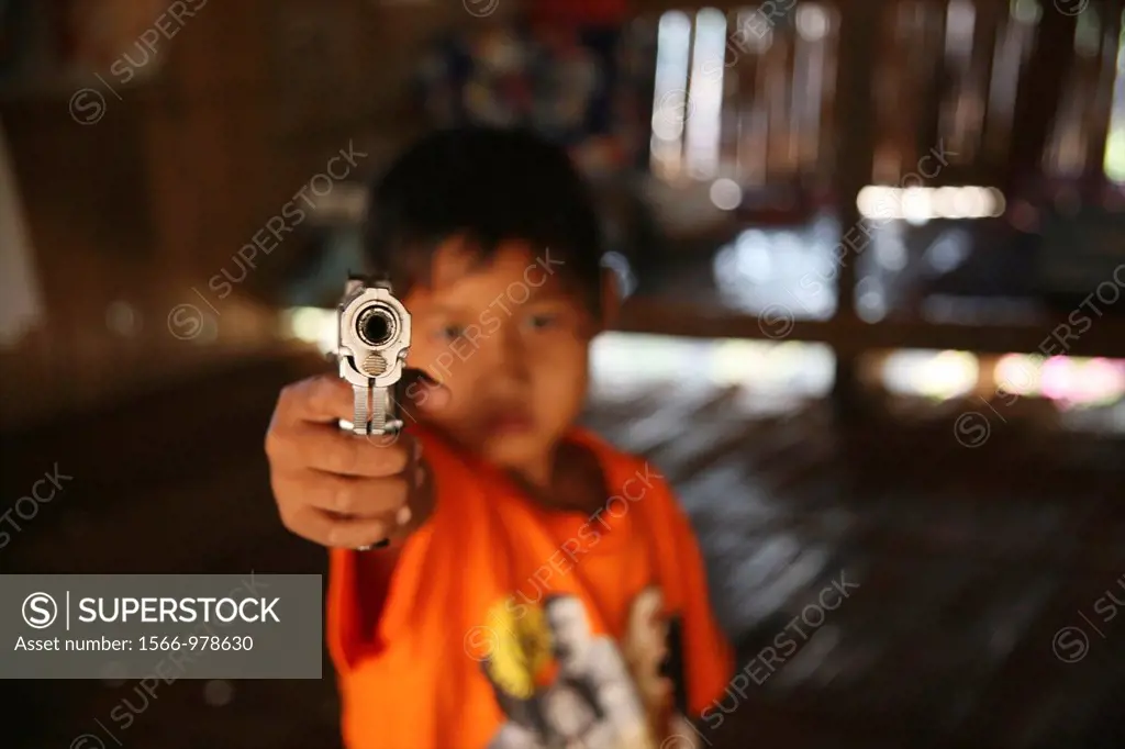 A young refugee aims a handgun at the camera Around 130,000 Burmese refugees have settled in Thailand due to opression in their homeland of Myanmar Bu...