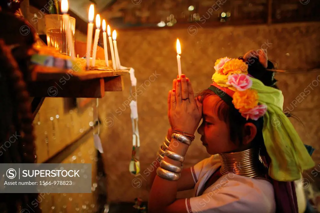 A young Longneck girls prays, holding a candle, at her family´s altar Approximately 300 Burmese refugees in Thailand are members of the indigenous gr...