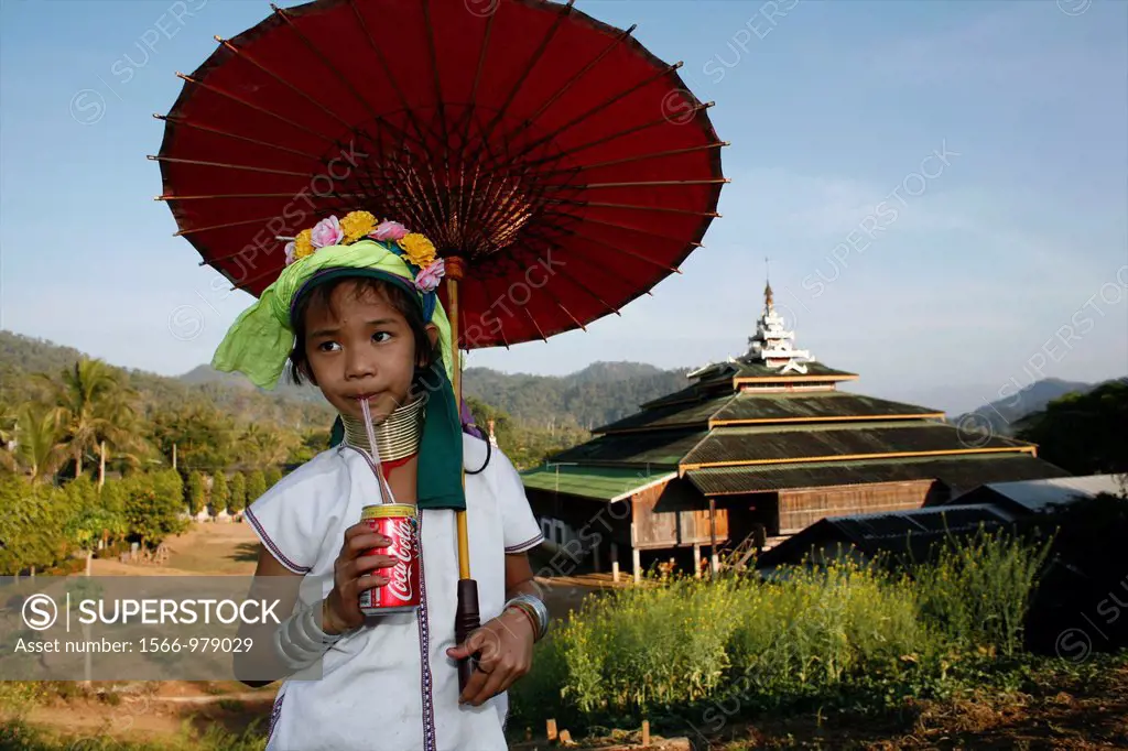 A young Longneck girl stands in front of a temple, drinking a Coke and holding a red parasol Approximately 300 Burmese refugees in Thailand are member...