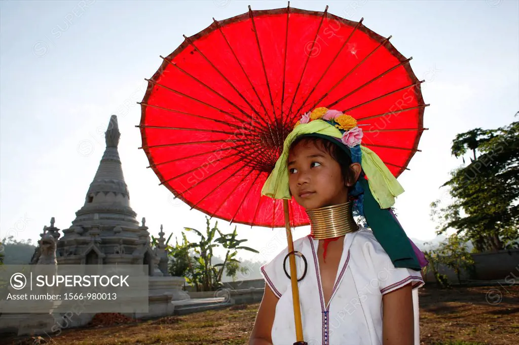 A young Longneck girl poses in front of a temple holding a bright red parasol Approximately 300 Burmese refugees in Thailand are members of the indige...
