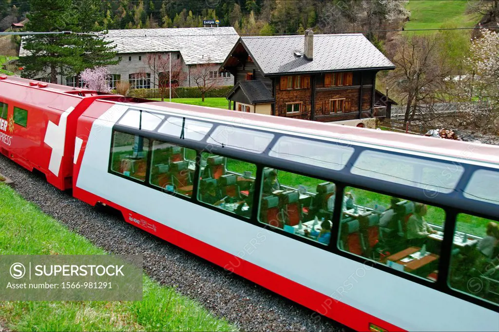 Swiss Glacier Express train passing little village in Valais canton, Wallis, Switzerland