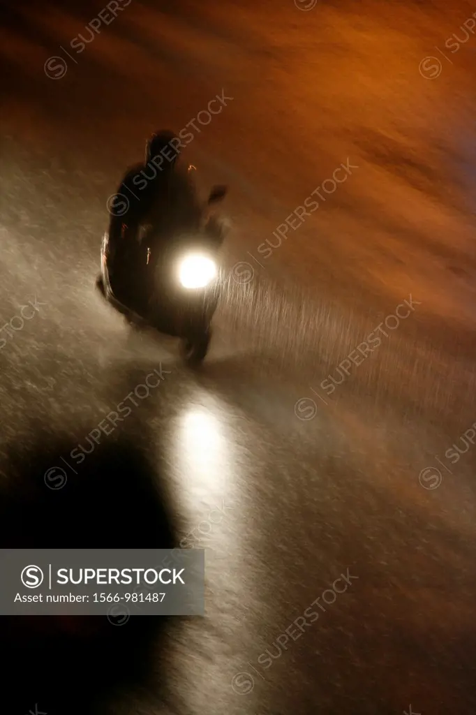 fast motorbike rider heavy rain at night in town