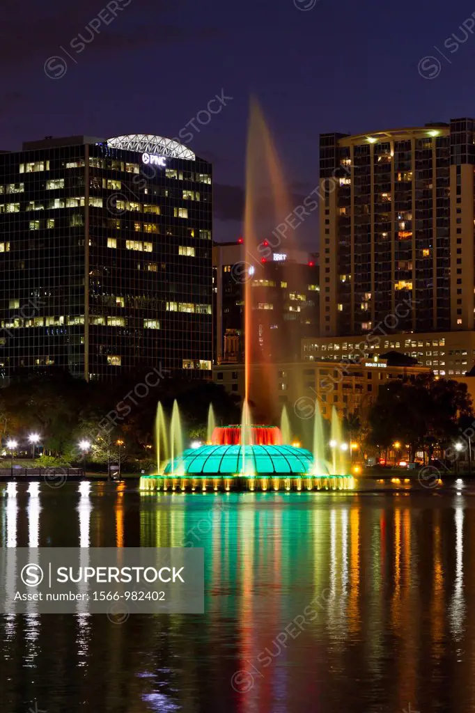 Eola Lake and downtown buildings with colorful water fountain at dusk in Orlando, Florida, USA