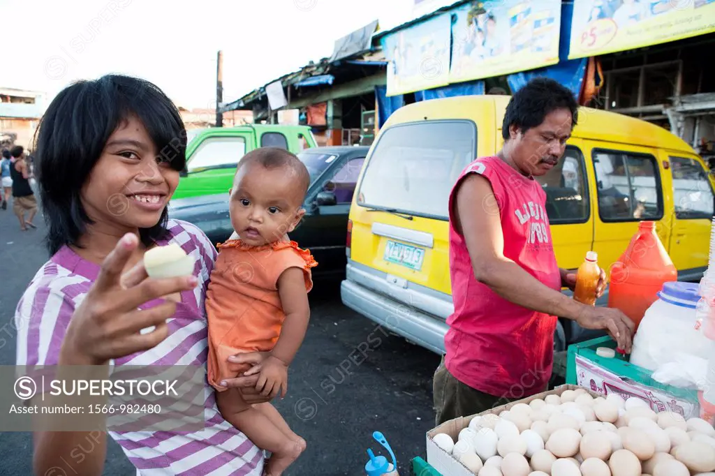 Woman with her baby, she is buying Balut, a fertilized duck embryo from a roadside vendor  Carbon Market, Cebu City, Cebu, Visayas, Philippines