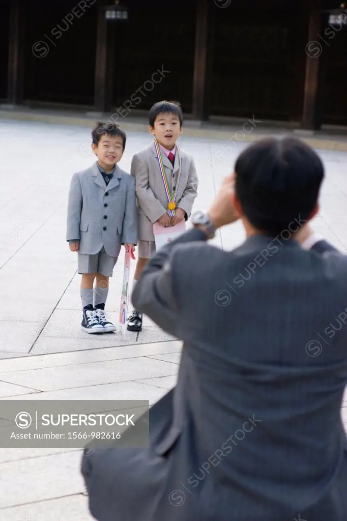 A man photographs two boys at Meiji-jingu shrine in Tokyo, Japan, Asia