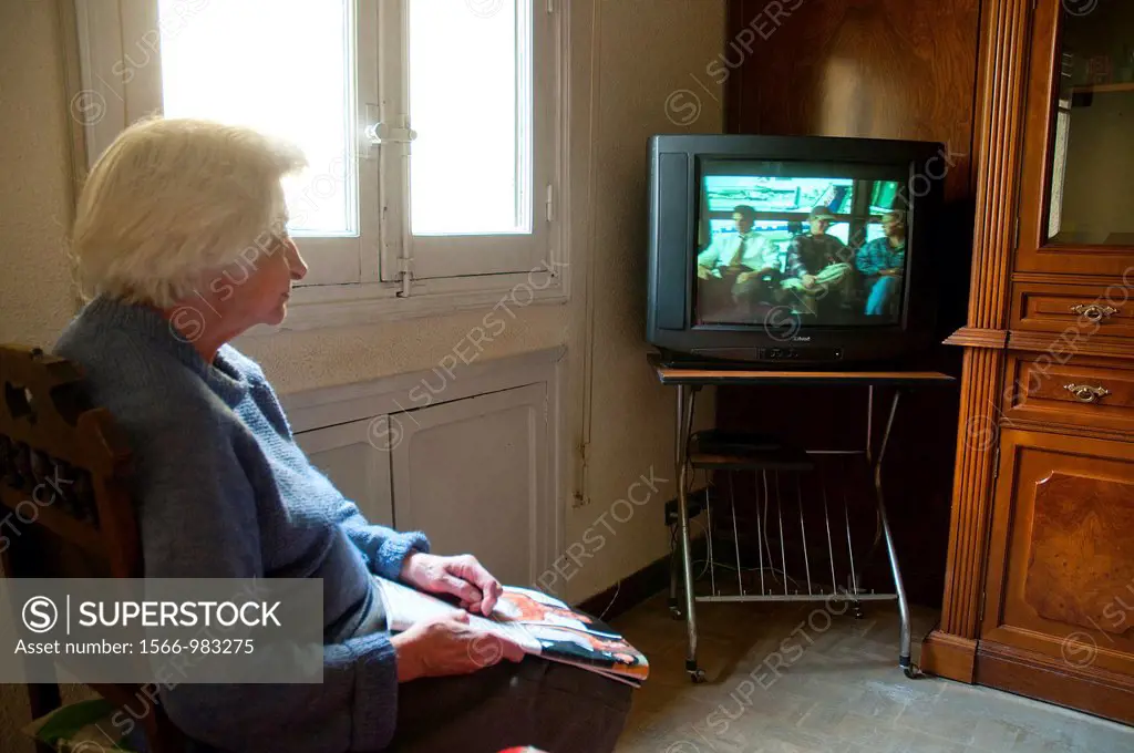 Old woman watching television at her home