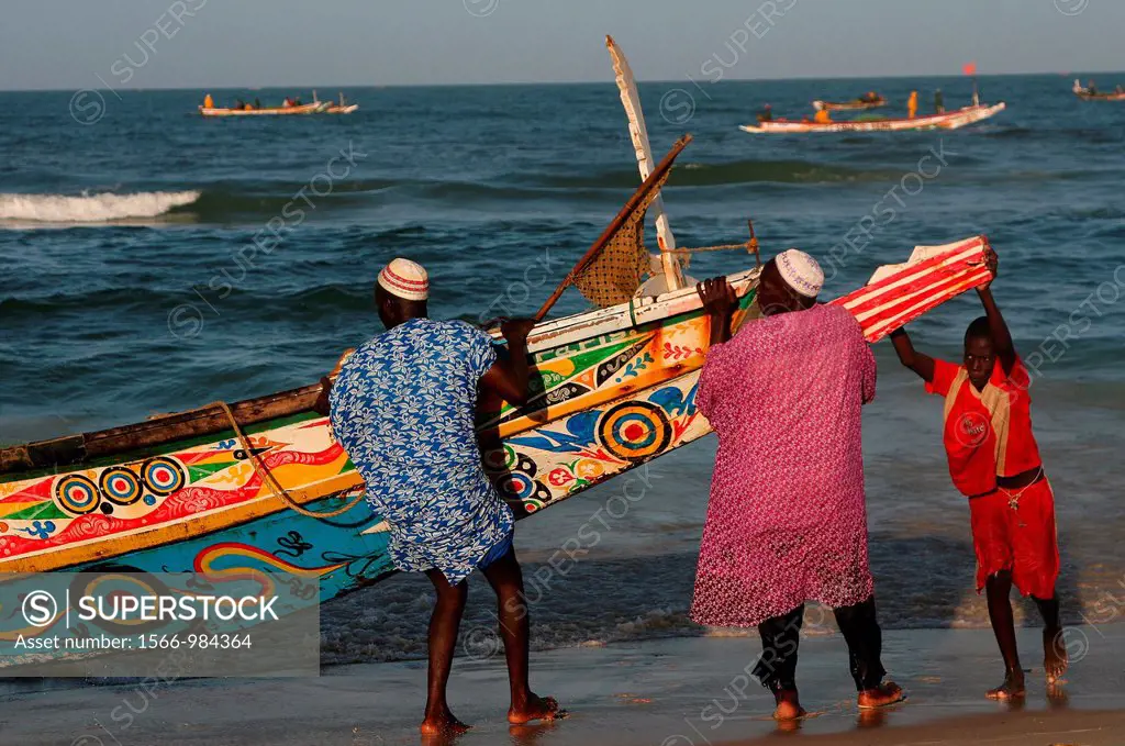 West Africa, Senegal, Saint Louis of Senegal, fishermen pulling a dugout at a beach of the Langue de Barbarie