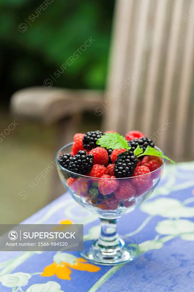 A glass bowl filled with raspberries and blackberries