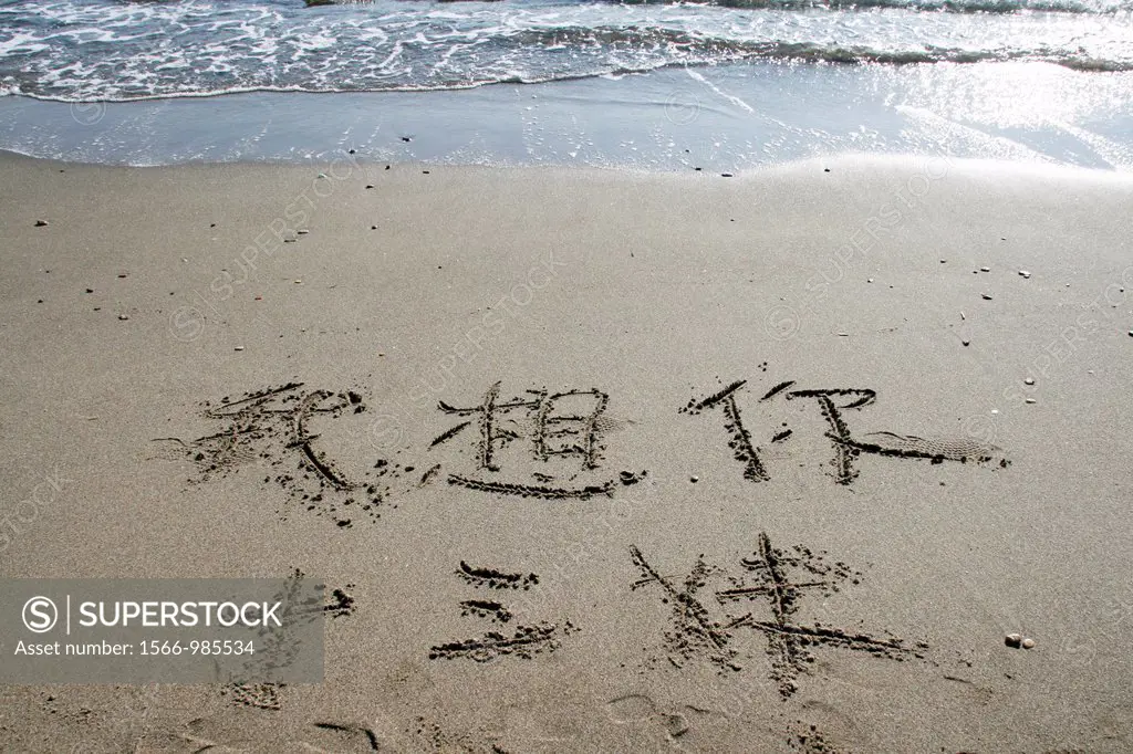 oriental words written in sand on empty beach