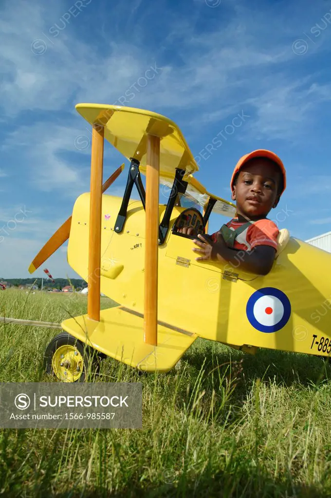 Young black boy sitting in a small biplane Tiger Moth