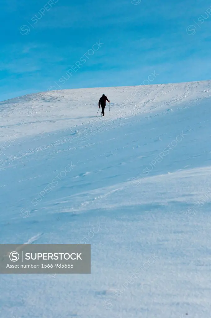 A lone man climbs a snow covered hill in Olympic park, Munich, Germany