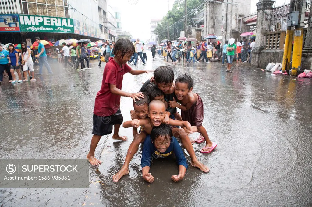 Cebu City, Philippines, 11 March 2012: Filipino kids having fun during a downpour as the raining season comes to an end