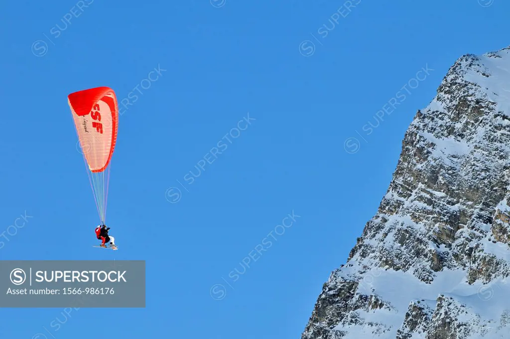 Two skiers paragliding close to a mountains cliff, Chamrousse, French Alps, France.
