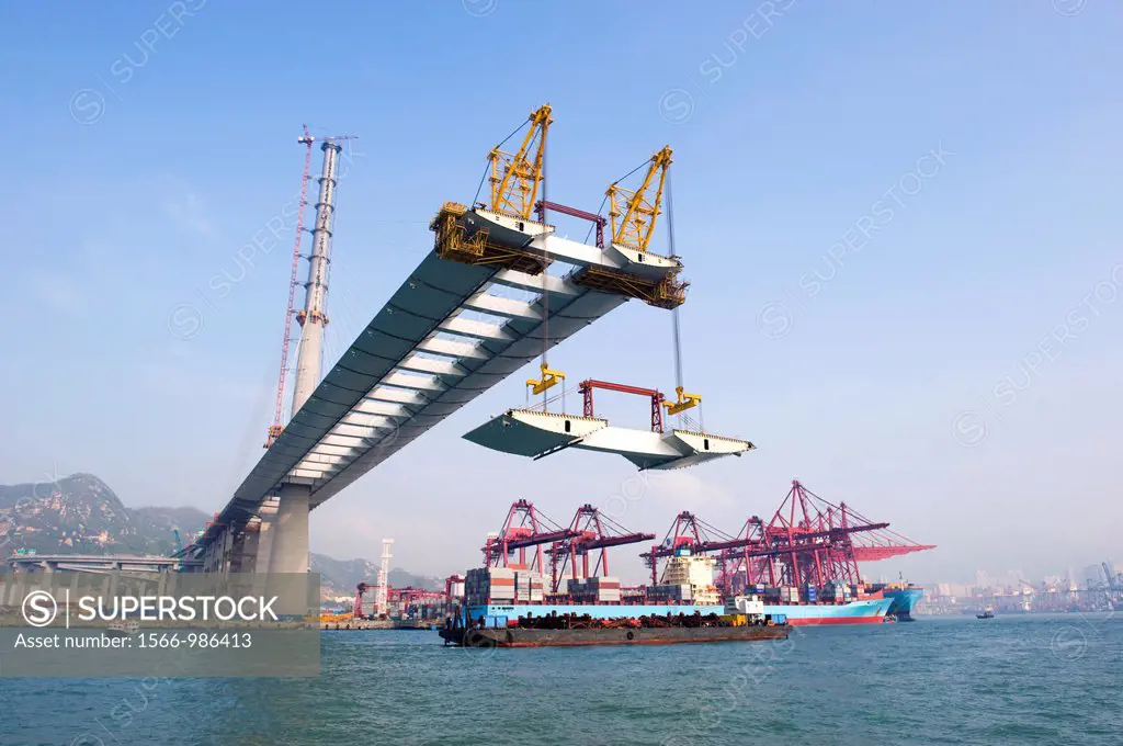 The raising of a section of the bridge deck of the StoneCutters Bridge seen from Rambler Channel in Hong Kong,with the Kwai Chung Container Port in th...