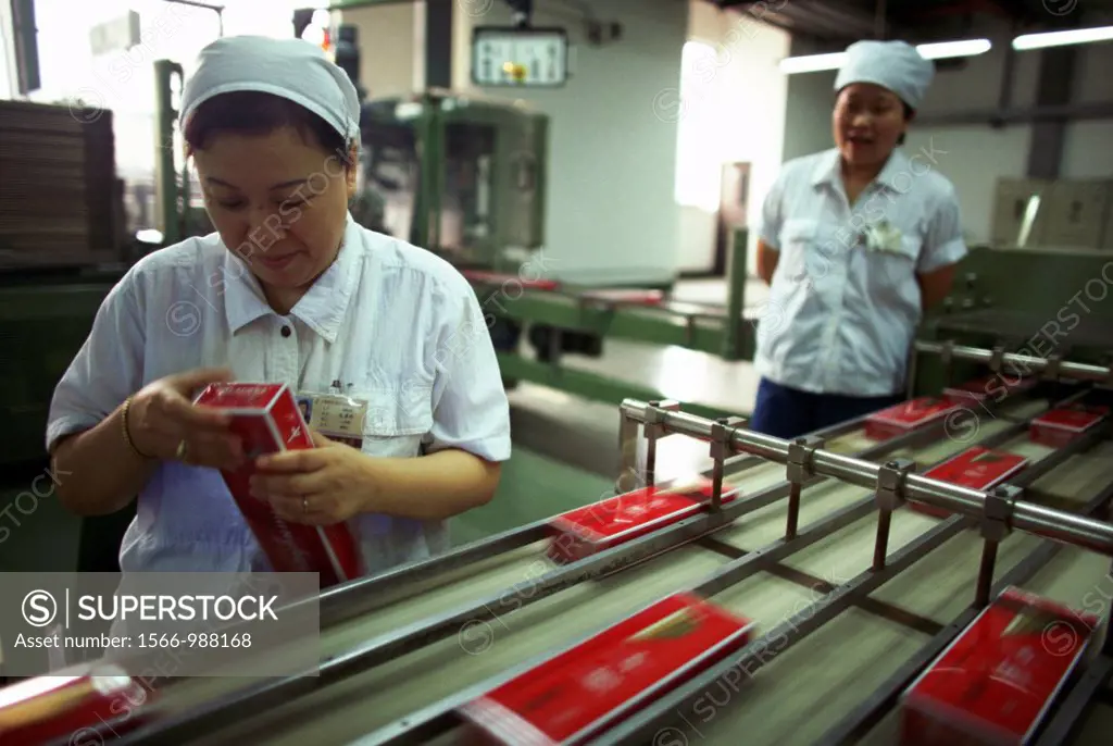 Women working on a cigarette manufacturing production line in Shanghai, China The factory is owned by the Shanghai Tobacco Company The woman is inspec...