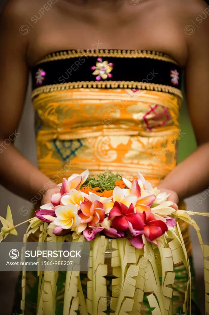 A close-up of Balinese woman holding a floral arrangement