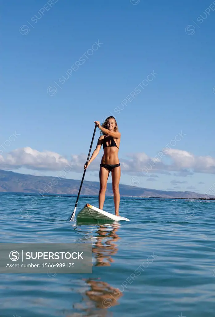 Healthy woman stand up paddles at Napili Bay, Maui, Hawaii