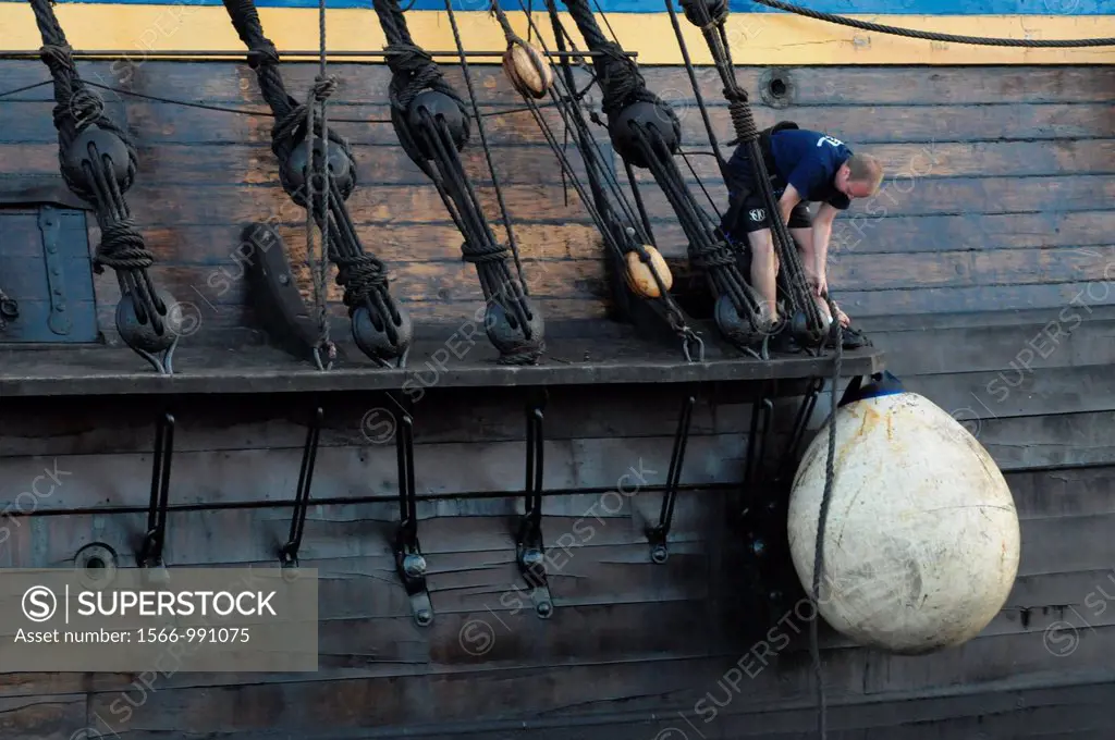 Sailor lashing back a fender at the hull of the Swedish 18th-century replica sailing ship Götheborg