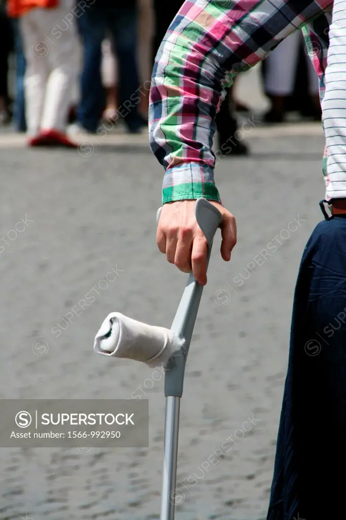 man with crutches in street road in city town
