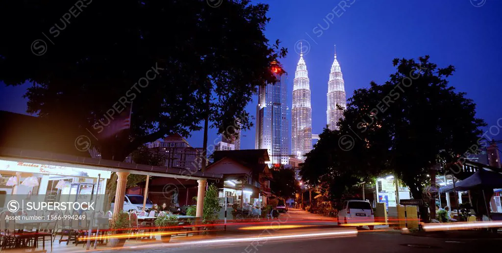 The Petronas Towers looming over local shops in the Malay area of Kampung Baru in Kuala Lumpur in Malaysia in Southeast Asia Far East. Kampung Baru is...