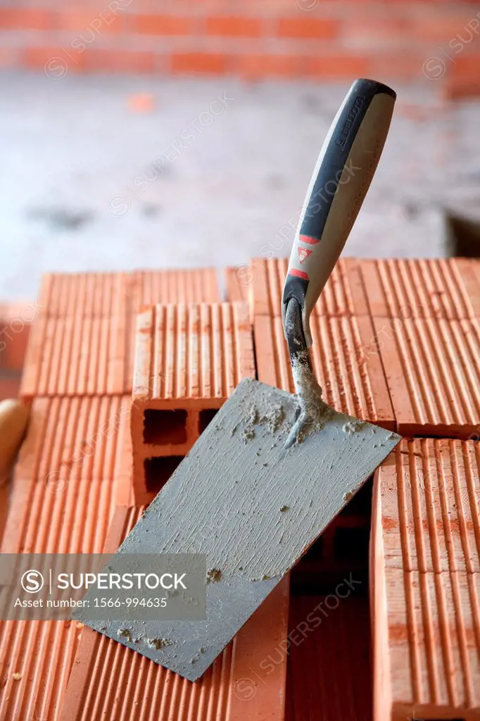 Construction worker with trowel, hand tools, Placement of brick with mortar on interior walls of housing, House Construction, Basque Country, Spain