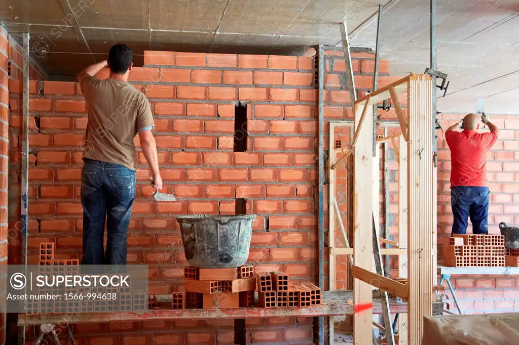 Construction worker with trowel, hand tools, Placement of brick with mortar on interior walls of housing, House Construction, Basque Country, Spain