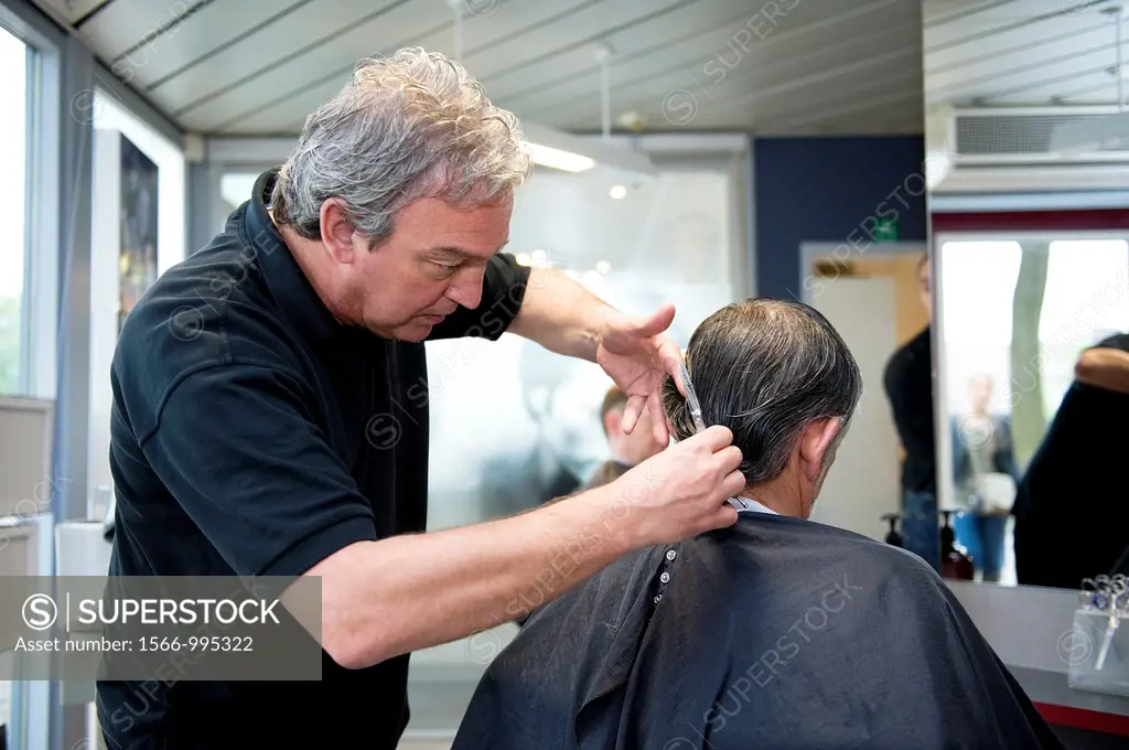Tilburg, Netherlands. A barber giving a customer a decent haircut.