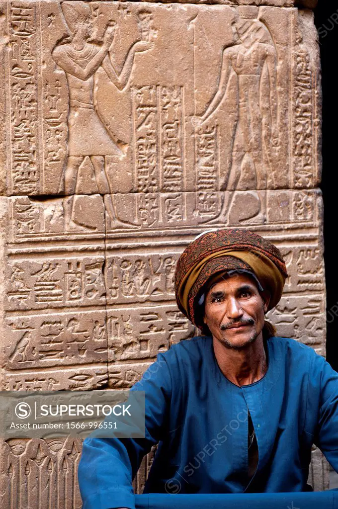 Egyptian man sitting in front of Horus Temple´s hieroglyphics  Edfu, Egypt