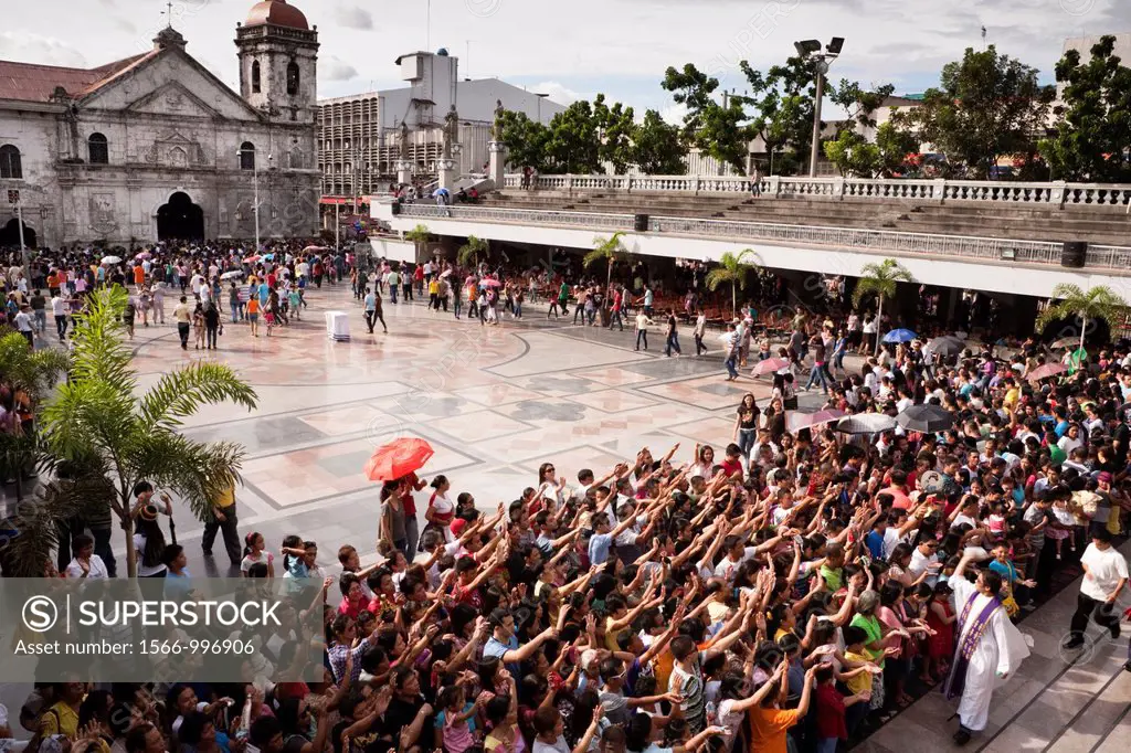 The priest blesses the crowd with holy water during an outdoor sunday mass at The Minor Basilica of the Santo Nino, aka Basilica Minore del Santo Nino...
