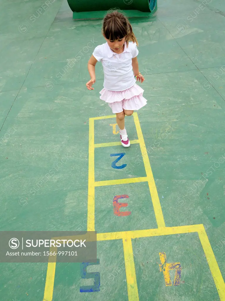 Four year old girl playing hopscotch in a children´s playground