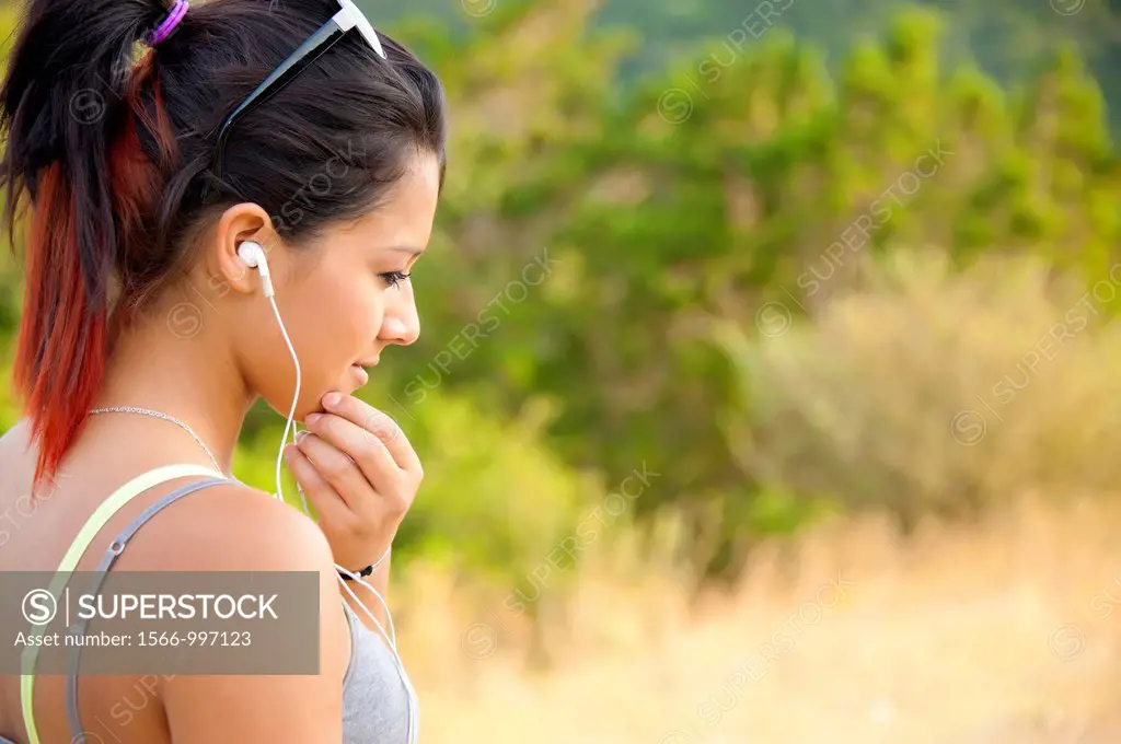 Young hispanic woman listening to music on her mp3 player