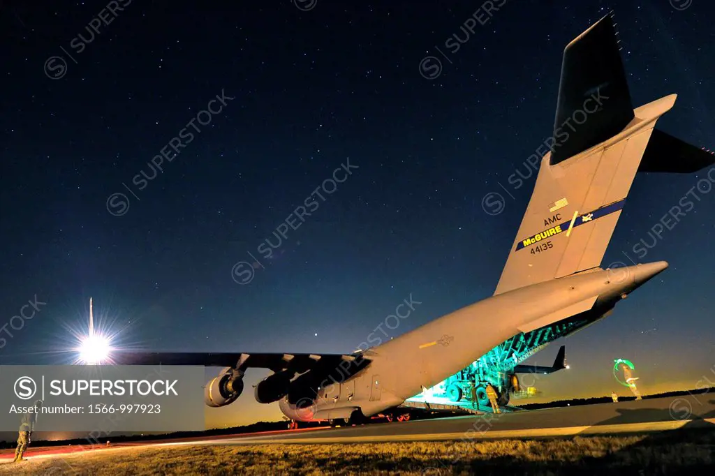 Aerial porters from the 621st Contingency Response Wing guide an articulated forklift from a C-17 Globemaster III during a nighttime engine-running of...
