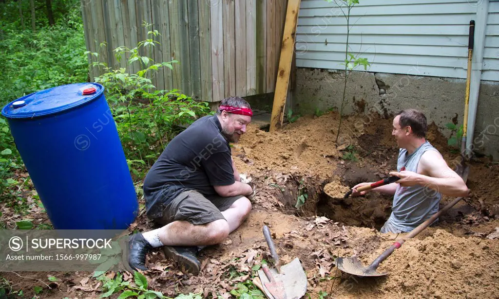 Prairieville, Michigan - Men dig a hole to install a dry well at a summer cottage that lacks most plumbing  Waste water from the kitchen sink will flo...