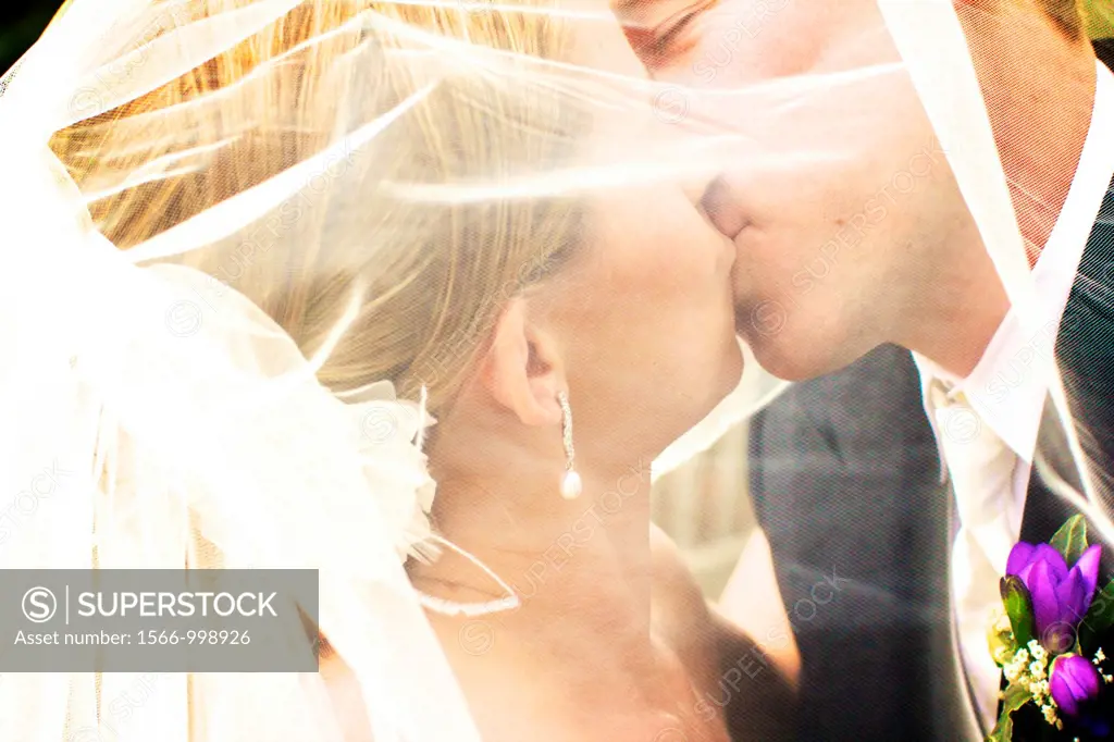 kissing through the veil - close up of bride and groom
