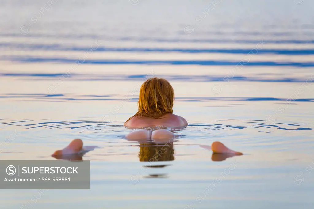 Floating in water with her back exposed young woman