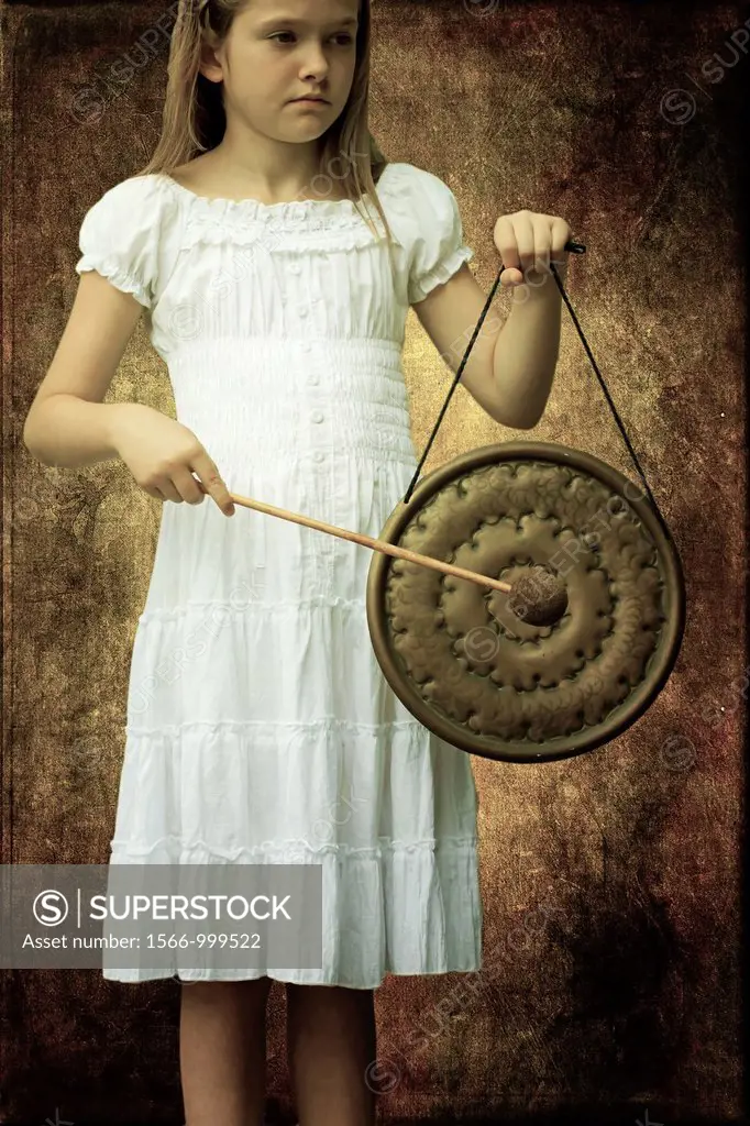 Girl in white dress strikes a gong