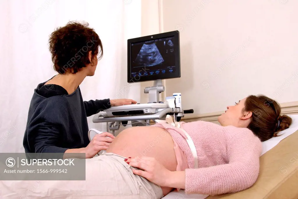Pregnancy ultrasound scan  Doctor using an ultrasound transducer to scan the abdomen of a heavily-pregnant 28-year-old woman