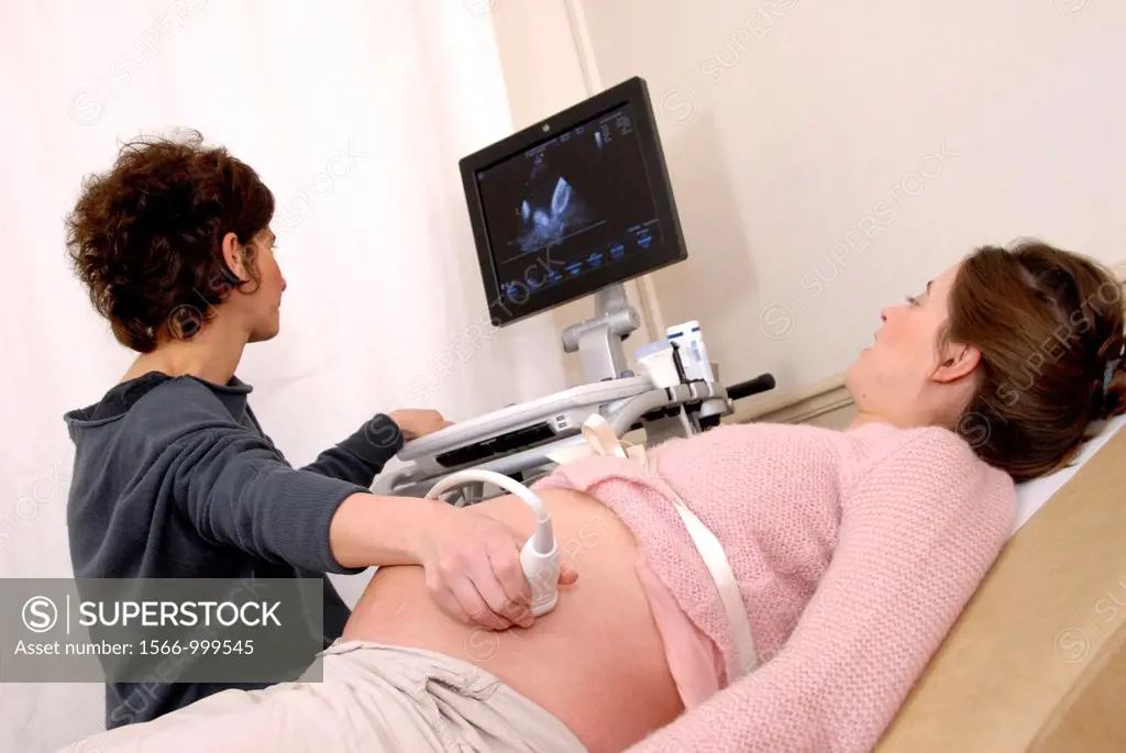 Pregnancy ultrasound scan  Doctor using an ultrasound transducer to scan the abdomen of a heavily-pregnant 28-year-old woman