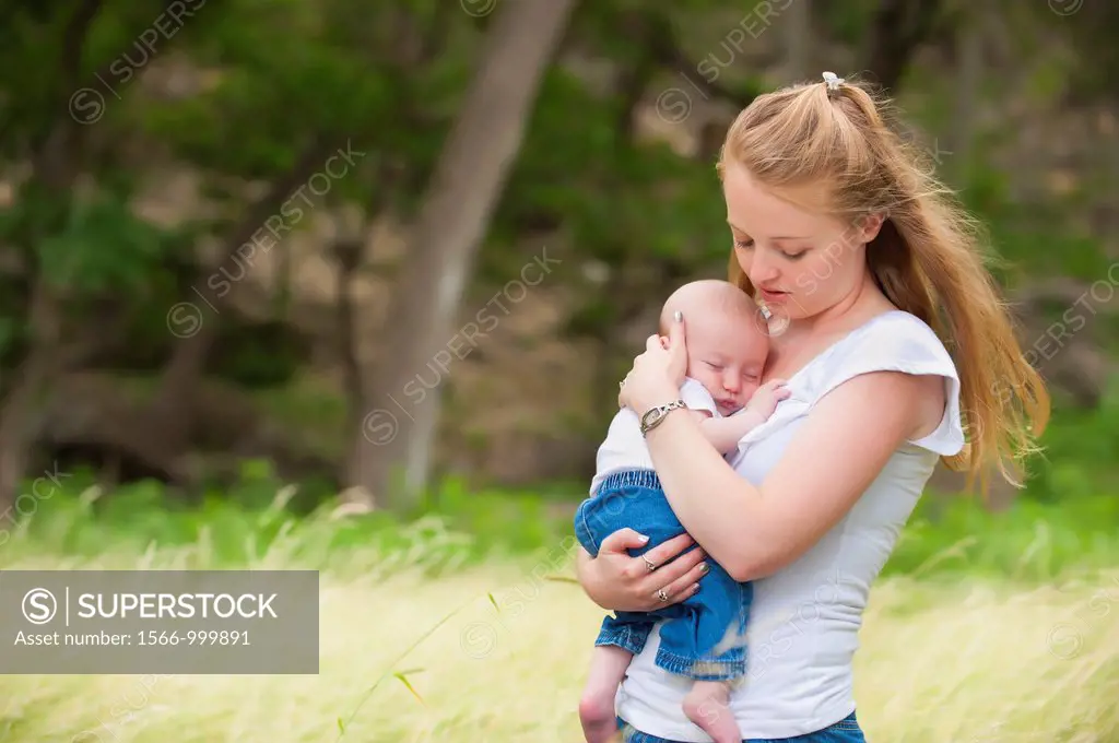 A young happy mother holding her four months old baby boy in a natural environment