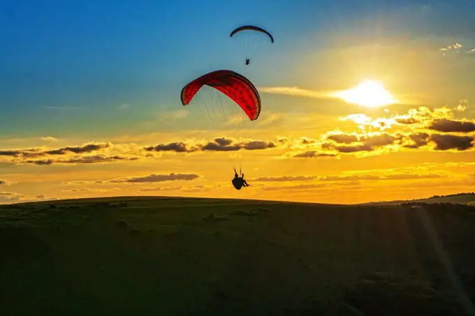 A Paraglider paraglides over the South Downs National Park during sunset. Uk.