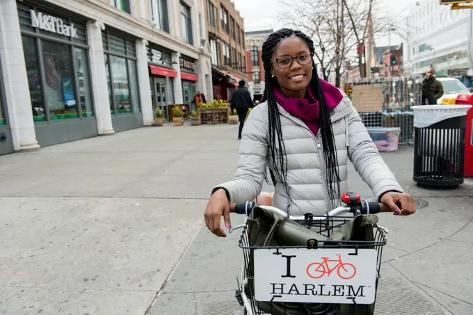 New York City, USA. Attractive African-American woman giving a guided tour by bicycle through Harlem, Manhattan.