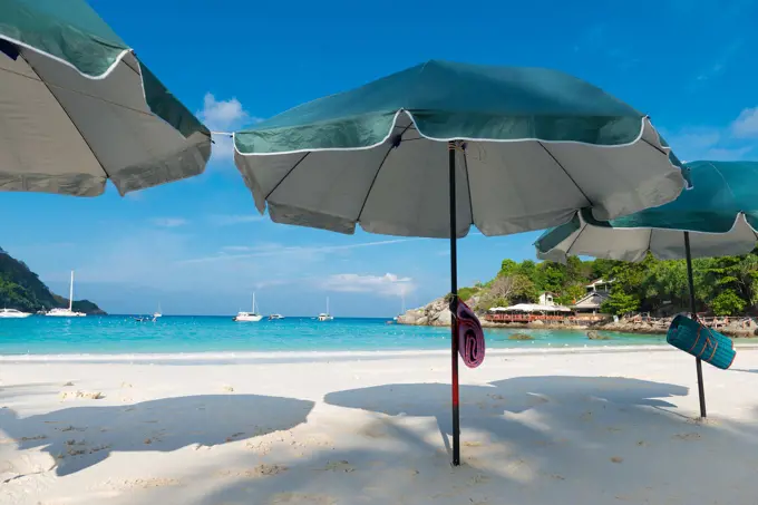Beach umbrellas waiting for tourists in Raya island, Thailand.