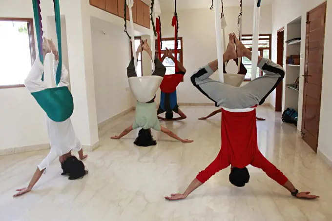 An aerial yoga class practicing Supta Baddha Konasana.