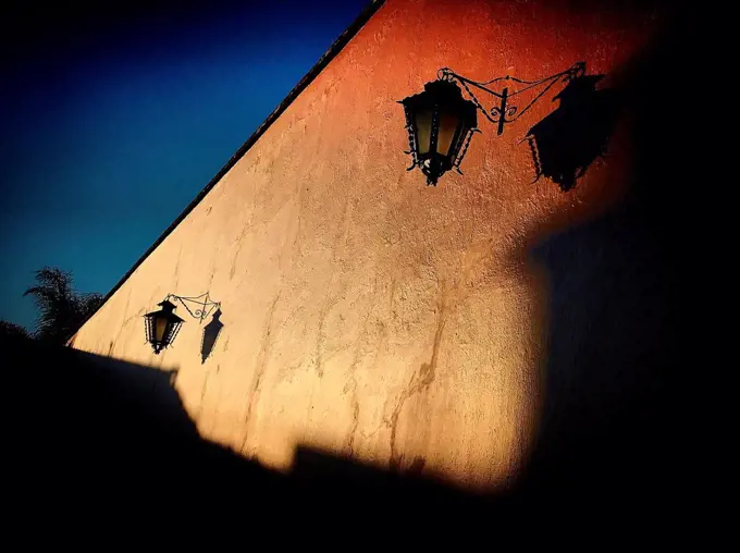 The shadow of a lamp is cast in an orange wall in Tequisquiapan, Queretaro, Mexico